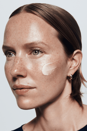 Close-up of a person with skincare product applied to their face against a neutral background